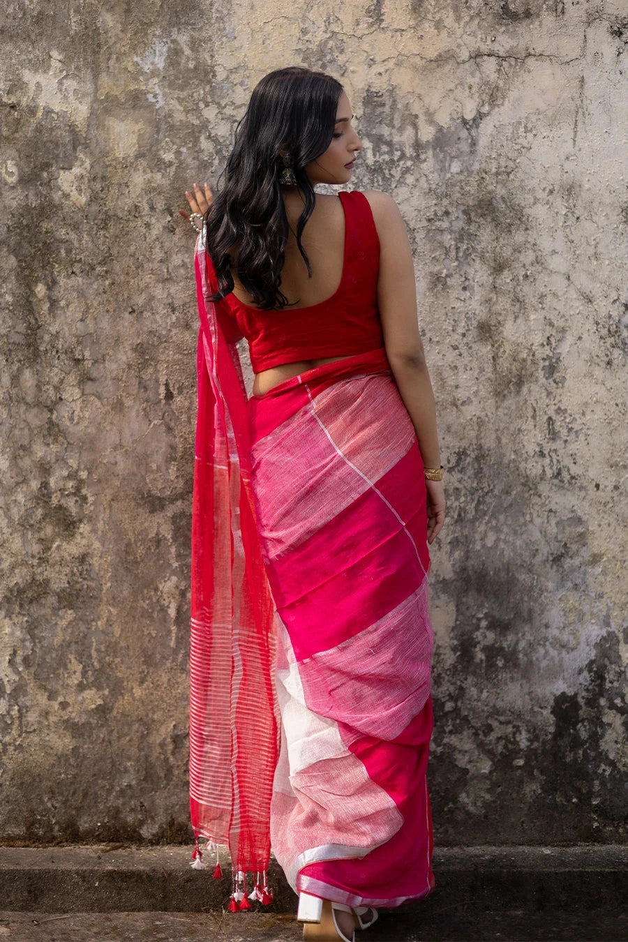 Woman wearing a red and white check red saree against a textured wall
