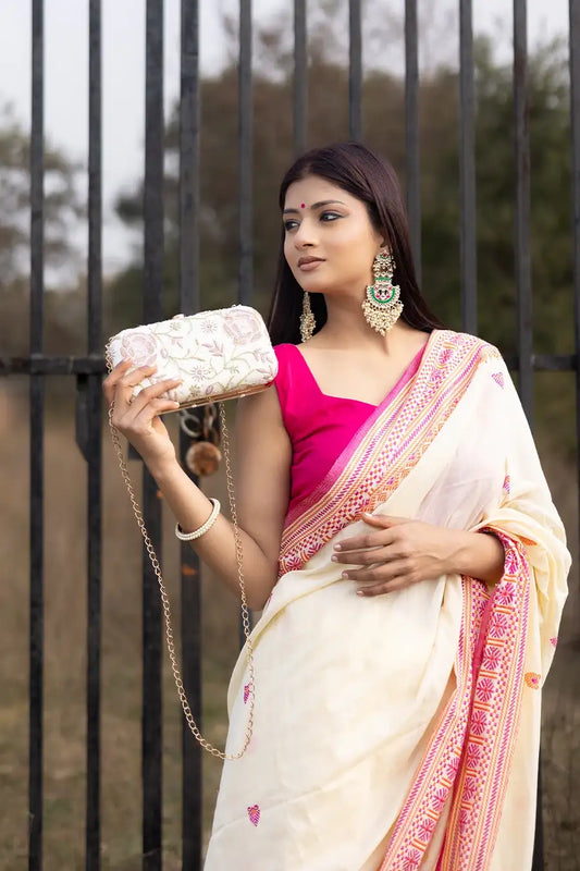 Woman wearing a white and pink saree with a black metal gate in the background