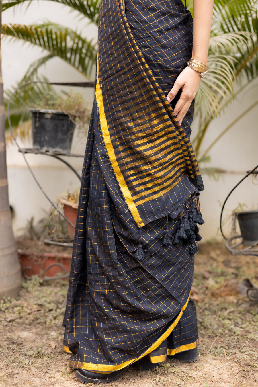 Model wearing a black and gold designer saree with a modern draped style suitable for festive and party wear.