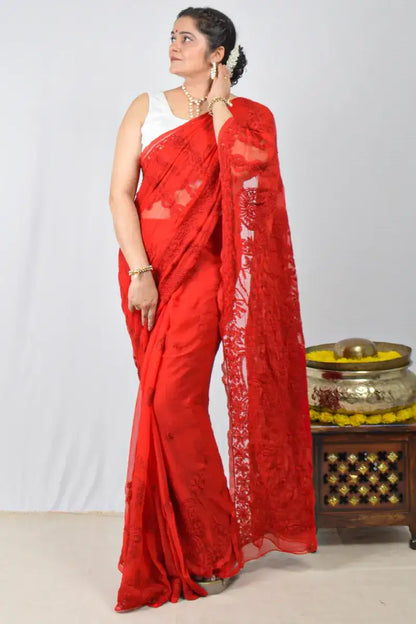 Woman wearing a red saree with a white blouse against a plain background