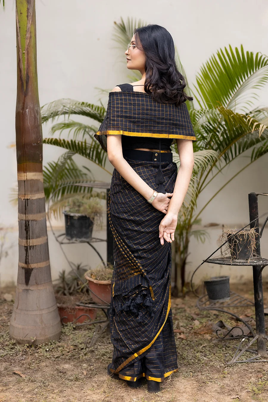 Model wearing a black and gold designer saree with a modern draped style suitable for festive and party wear.