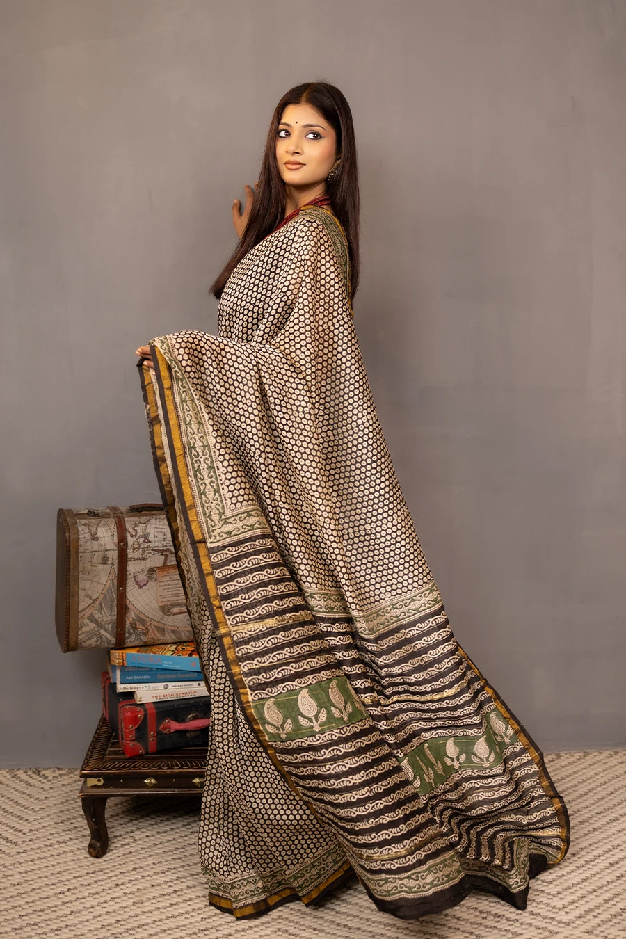Woman wearing a patterned saree with a grey background