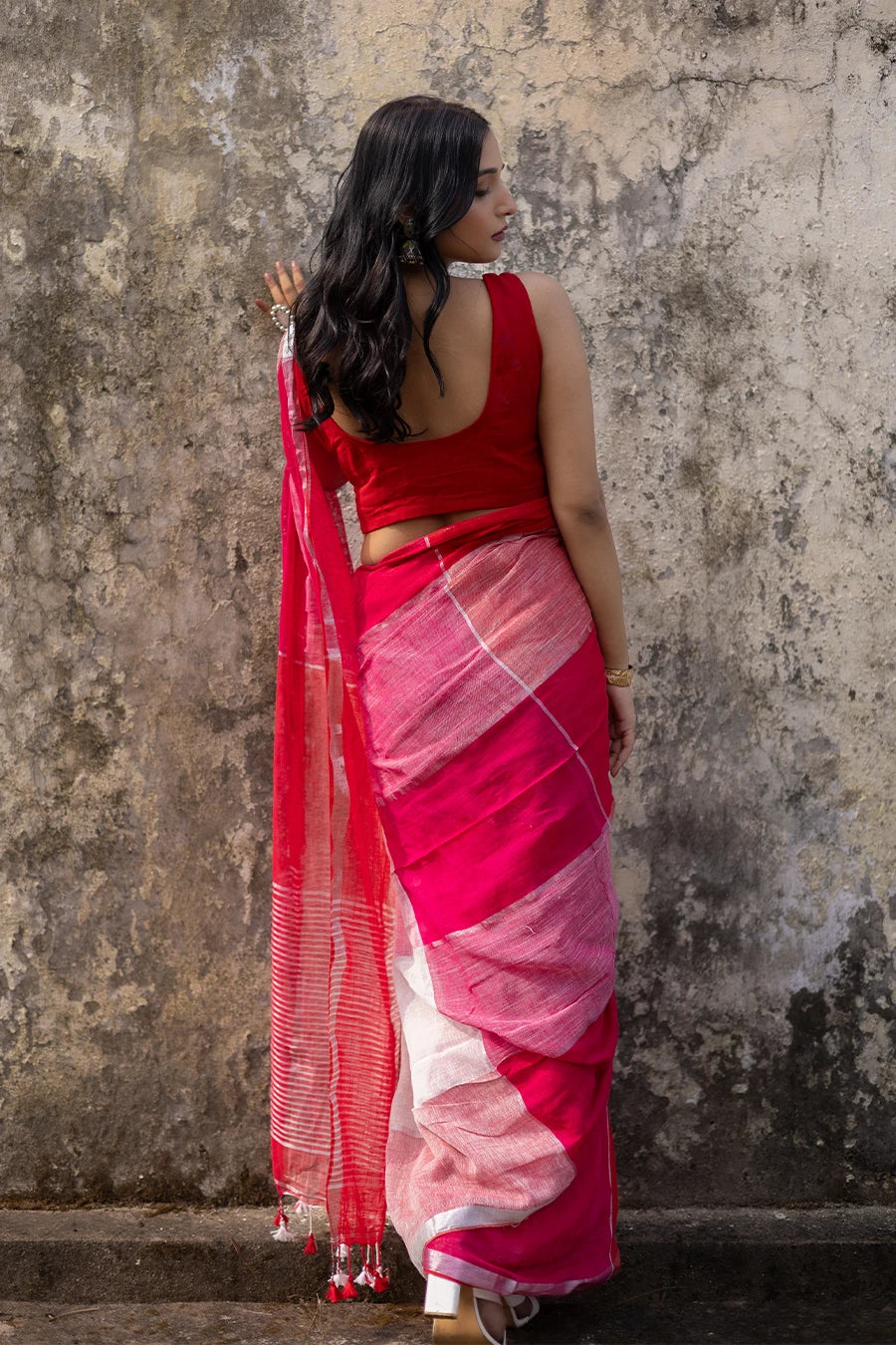 Woman wearing a red and white check red saree against a textured wall