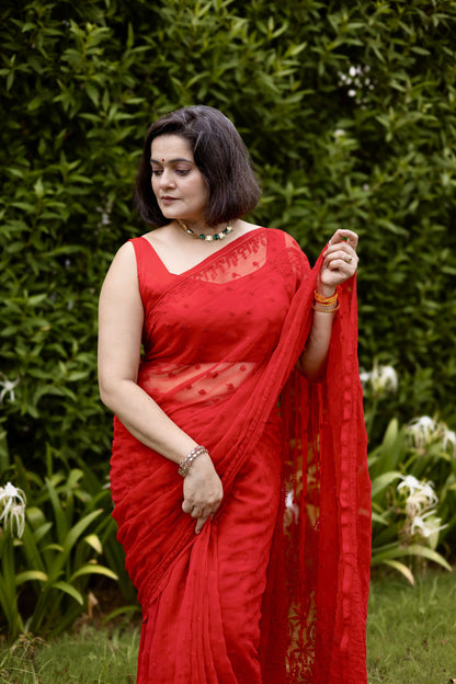 Front view of woman in red georgette chikankari saree with blouse, holding pallu
