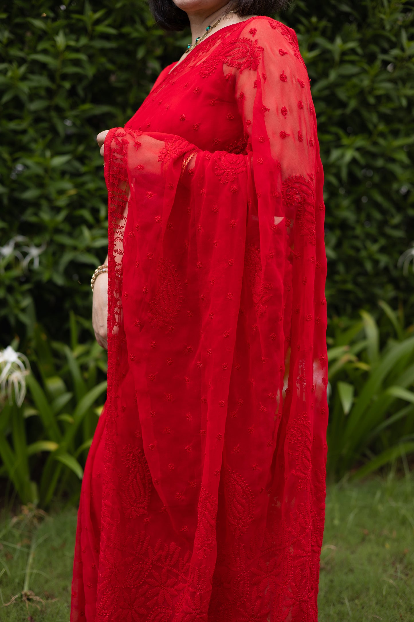 Side drape view of red georgette Lucknowi chikankari saree showing embroidery detail