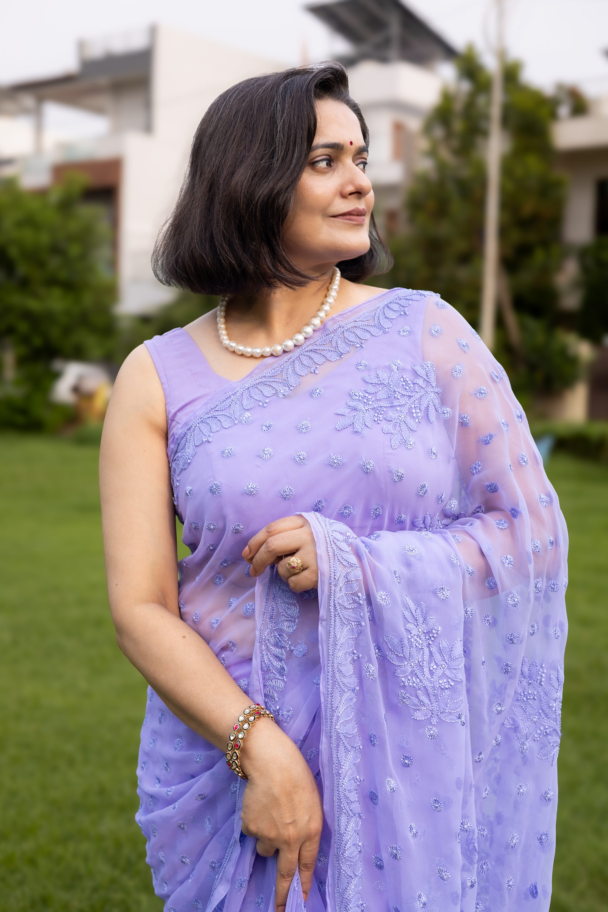 Woman in lavender georgette chikankari saree with blouse, side profile in garden