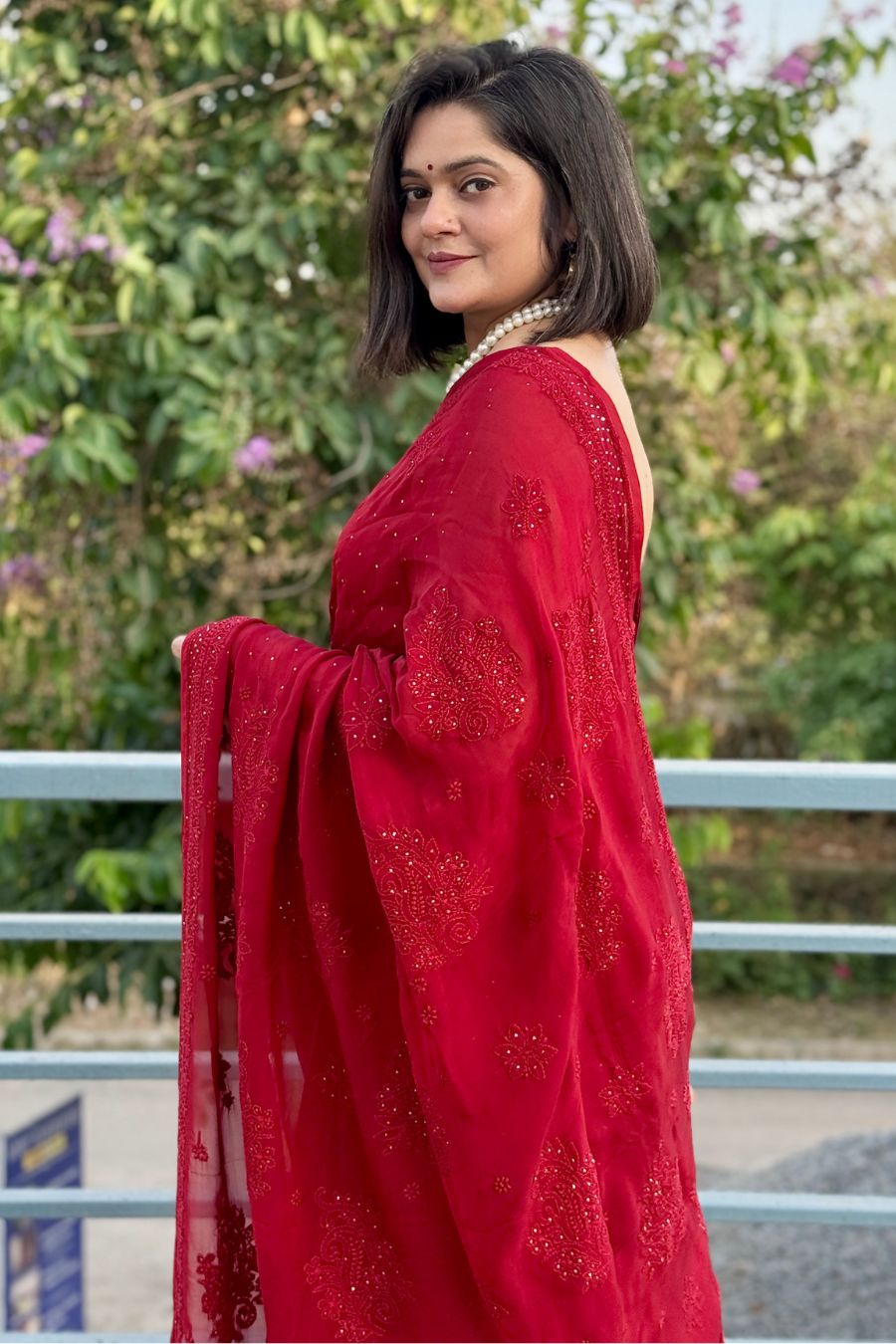 Model wearing red organza chikankari saree with mukaish work, festive drape view.