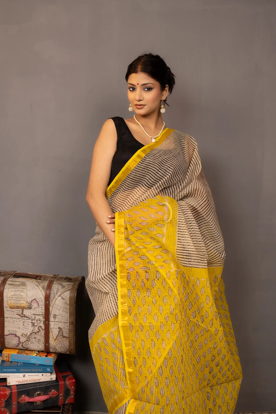 Woman wearing a beige and yellow saree with a grey background